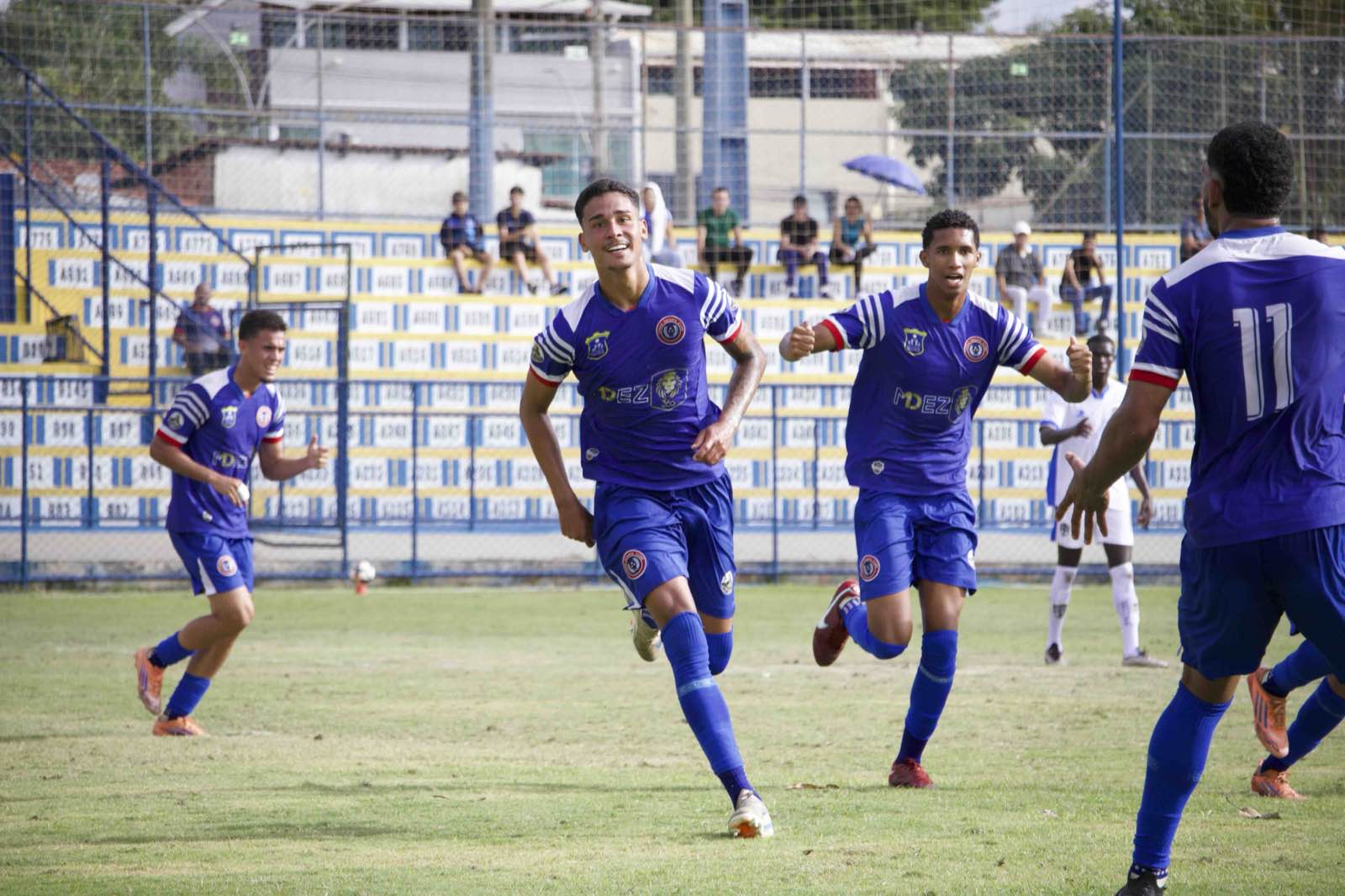 Atletas do Canaã correndo abraçados para comemorar um gol.