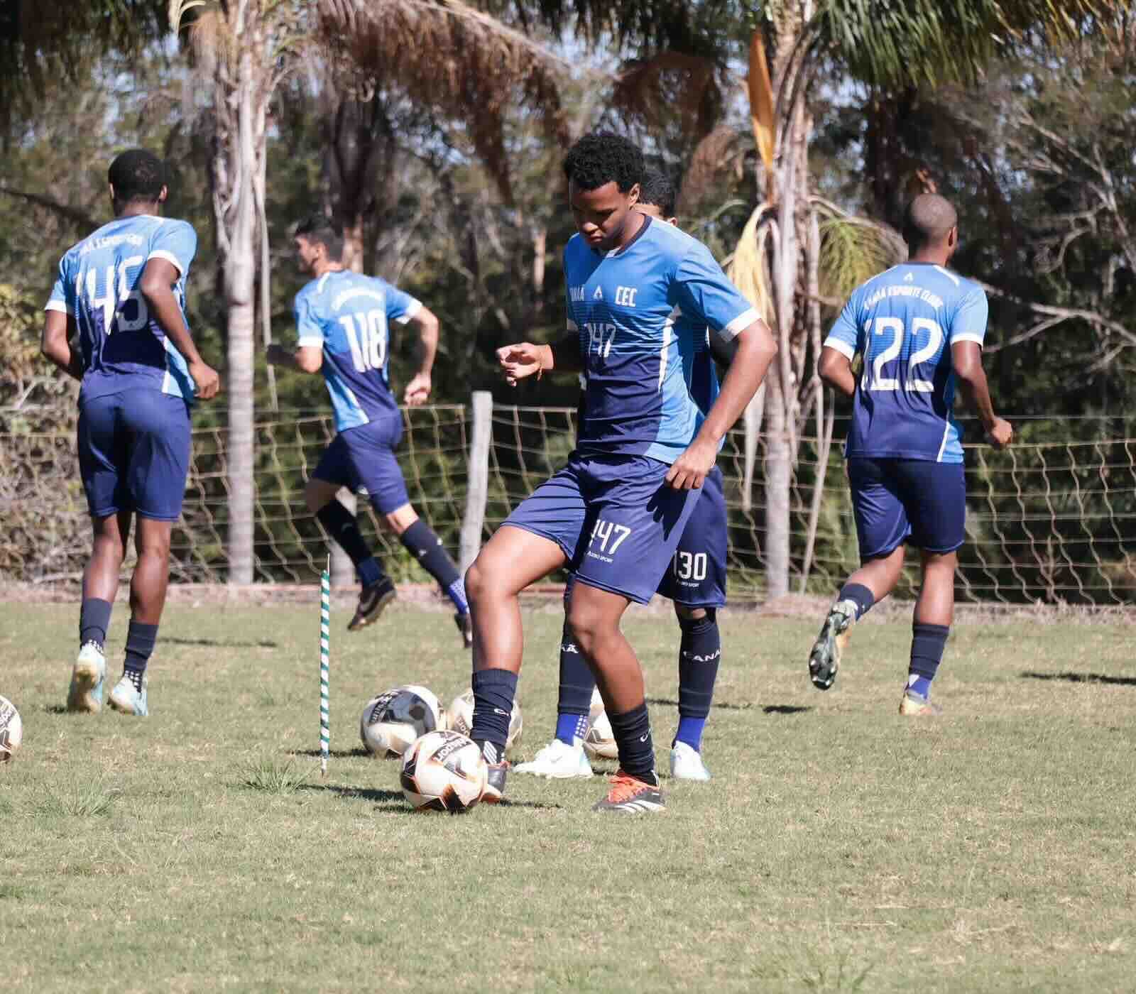 Atletas do Canaã conduzindo a bola em treino coletivo no campo.