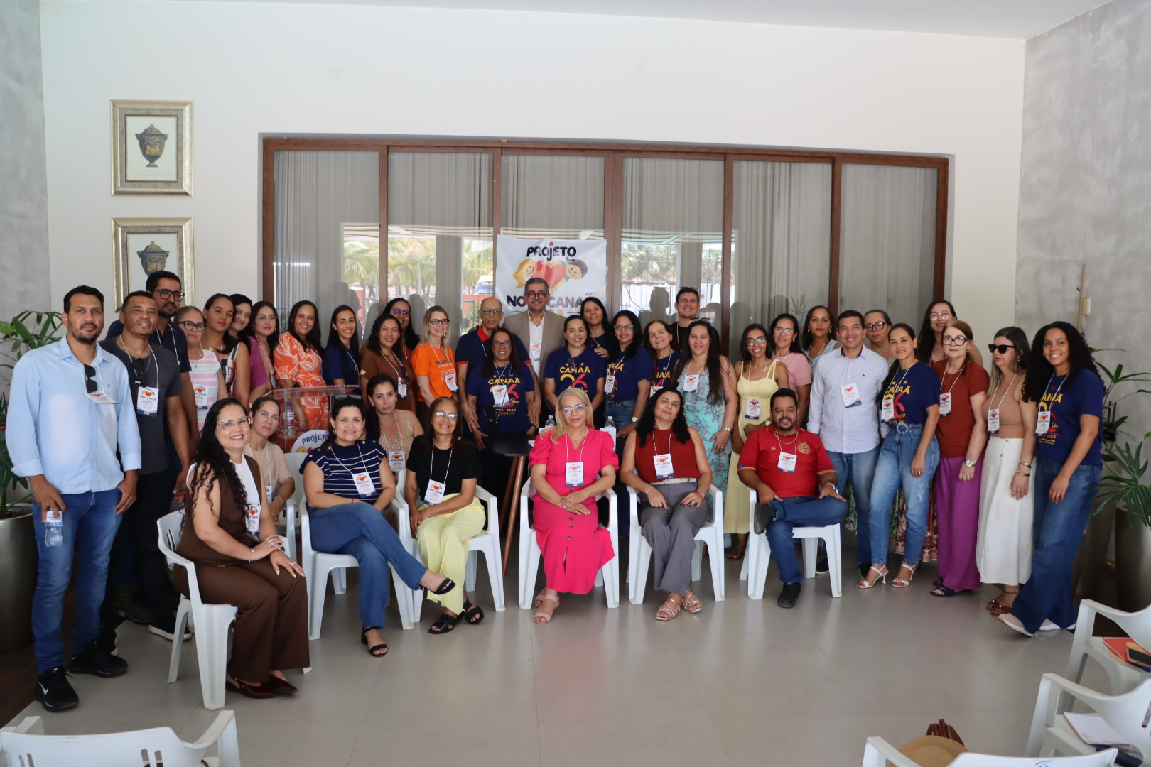 Participantes reunidos para uma foto de grupo, com pessoas sentadas à frente e outras em pé diante do banner do congresso.